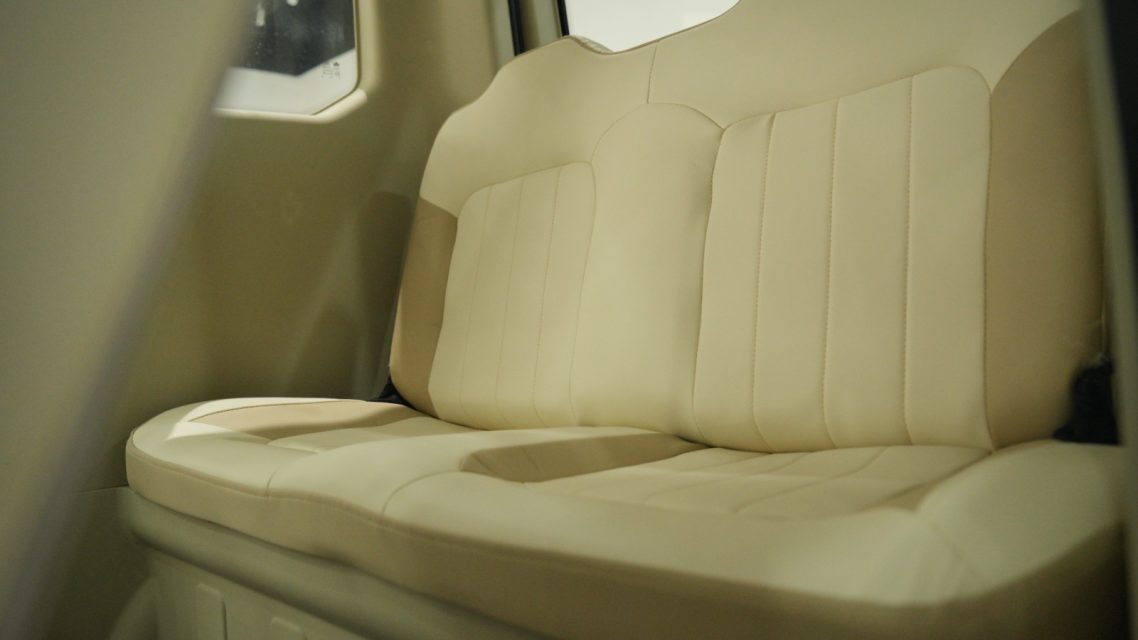 Rückbank Beige Rückbank mit gepolsterten Sitzen und vertikalen Nähten.